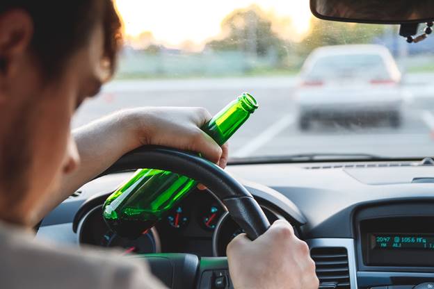 A person holding a bottle of beer while driving
AI-generated content may be incorrect.